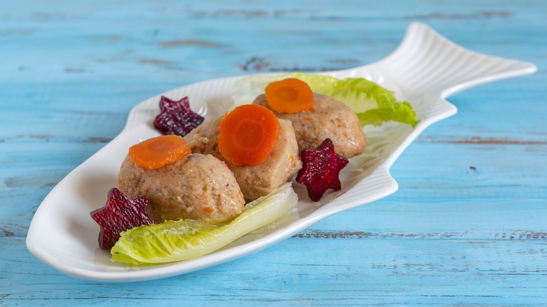 Gefilte fish with carrots, lettuce leaves, and beets cut into star shapes served in a fish-shaped dish