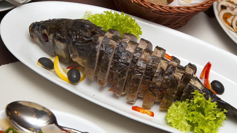 Gefilte fish on a platter presented in slices in the shape of a body of a fish, with the head of the fish it was made from at the top