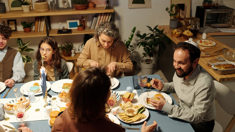 A Jewish family happily eating and chatting at the dinner table