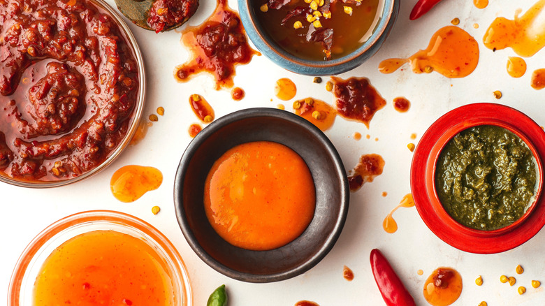 Various types of sauces in bowls on white table