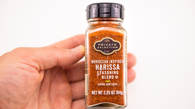 Hand holding jar of harissa seasoning blend