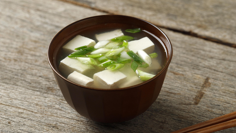 miso soup with tofu and scallions in brown bowl