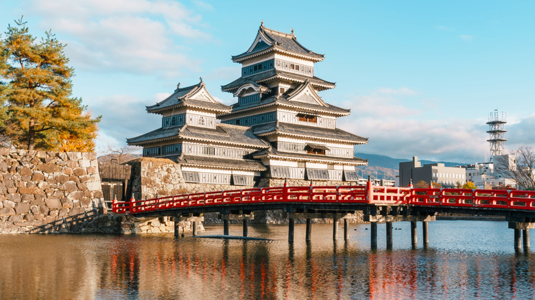 Matsumoto castle against blue sky with water in foreground