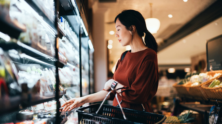 woman shopping in refrigerated section of grocery store
