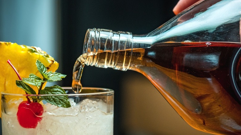 Hand pouring rum in cocktail