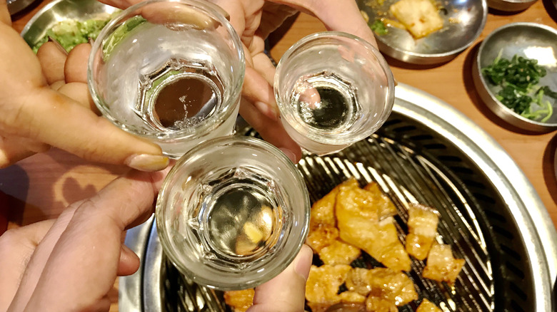 People toasting with soju at a meal