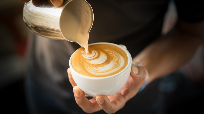 Person pouring steamed milk into espresso