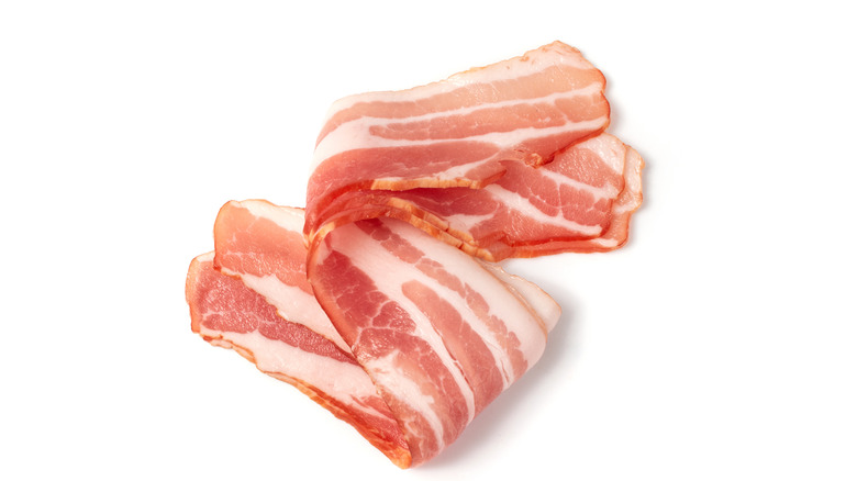Curled slices of bacon on white background