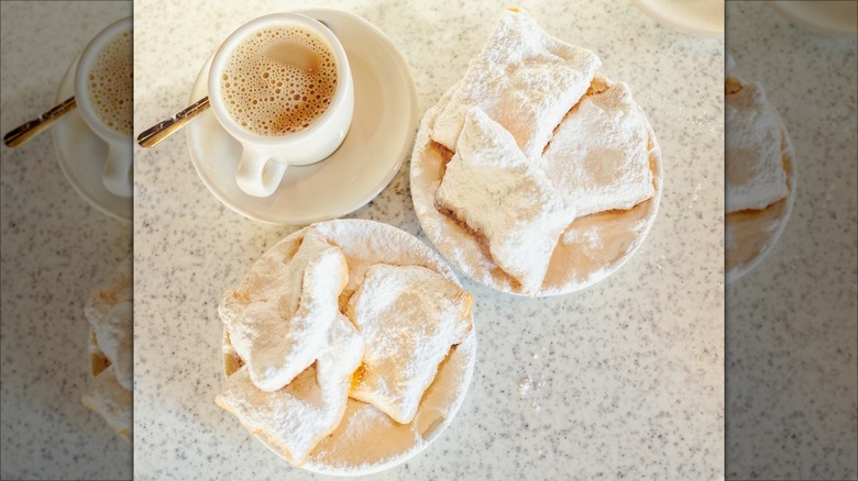 Overhead view of beignets on a plate with coffee
