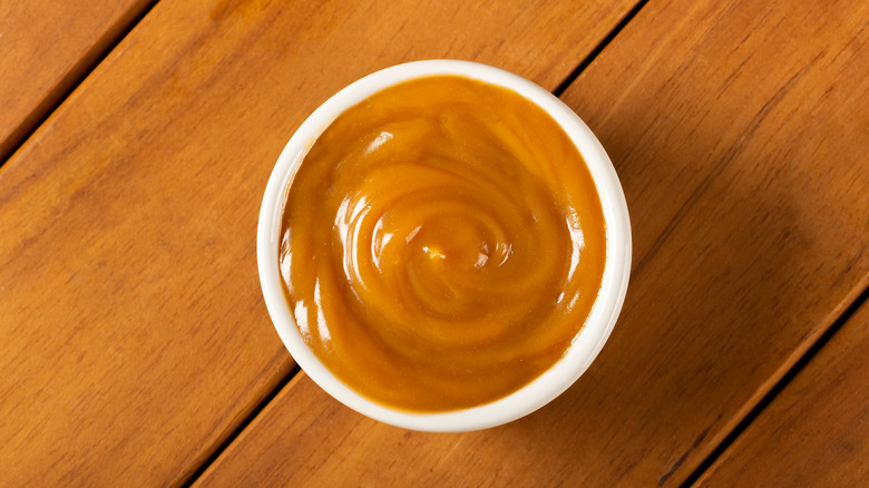Dulce de leche in a white bowl on wooden table