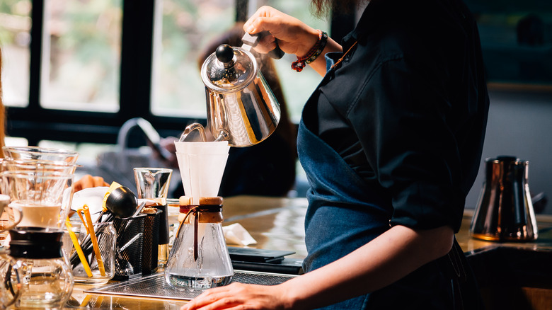 Barista using a pour-over coffee device