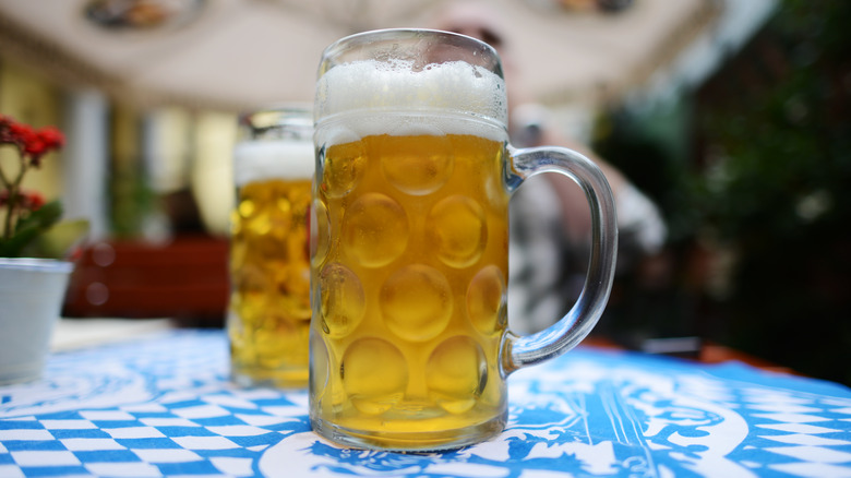 Two mugs of light-colored lagers sitting on a table