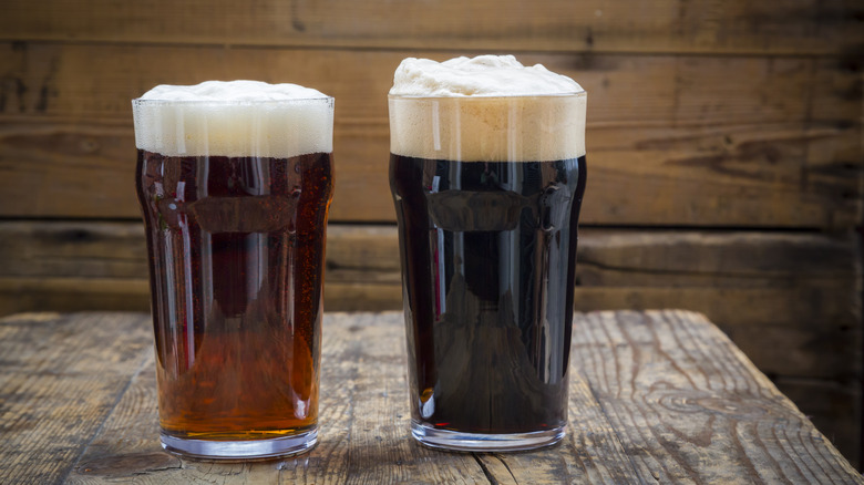 Two foamy glasses of beer, one that is an amber color and one that is very dark