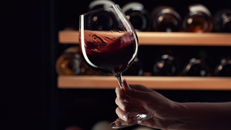 A person swirling red wine in a stem glass