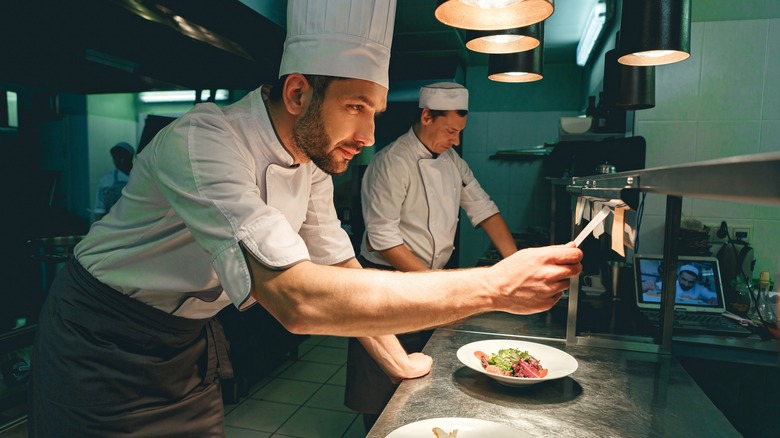 A chef checking an order ticket at a professional restaurant kitchen.