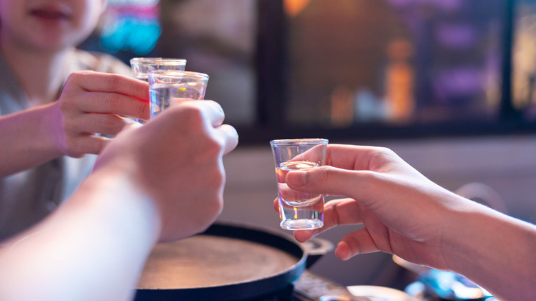 A group of people toasting with shots of soju