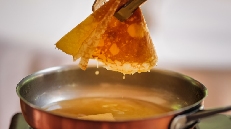 Crêpe being lifted from a pan with tongs