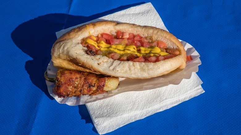 Sonoran hot dog on top of a napkin on a blue background