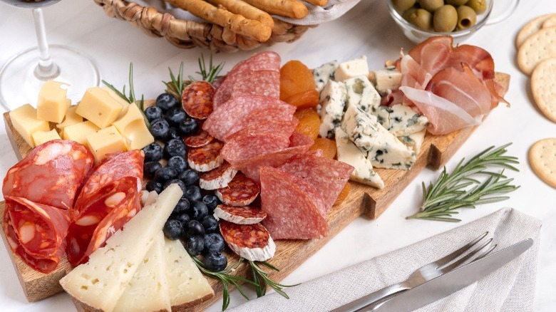 Antipasti surrounded by crackers, breadsticks, and olives