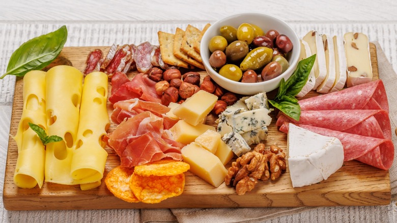 Board filled with meat, cheese, and snacks