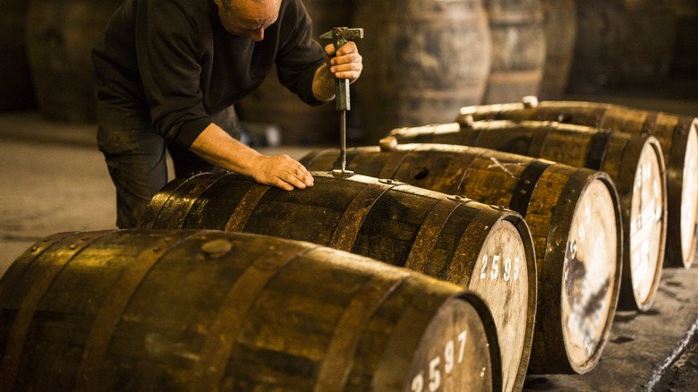 Distiller checks barrel of whiskey