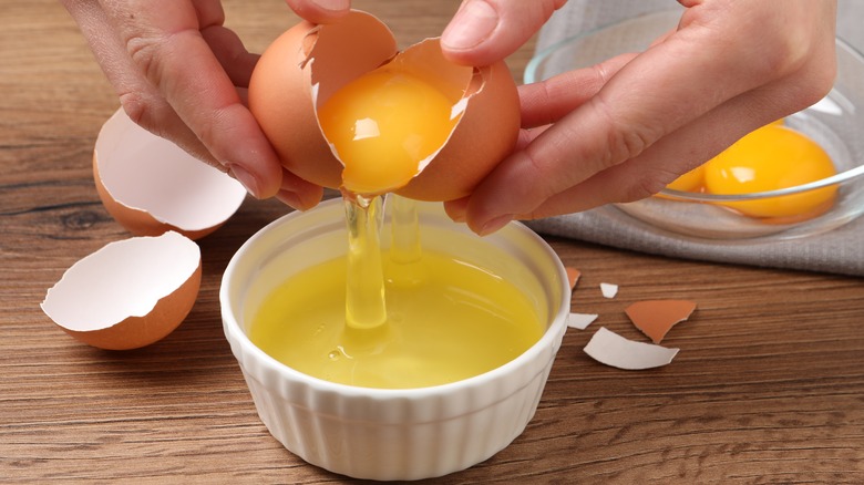 A person cracks open an egg to separate its yolk.