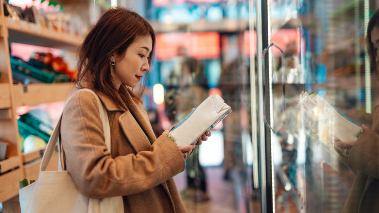 A person reads a product label in a supermarket.