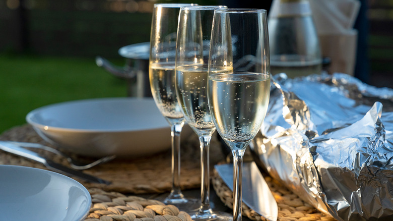 Three filled sparkling wine glasses on a table set for barbecue