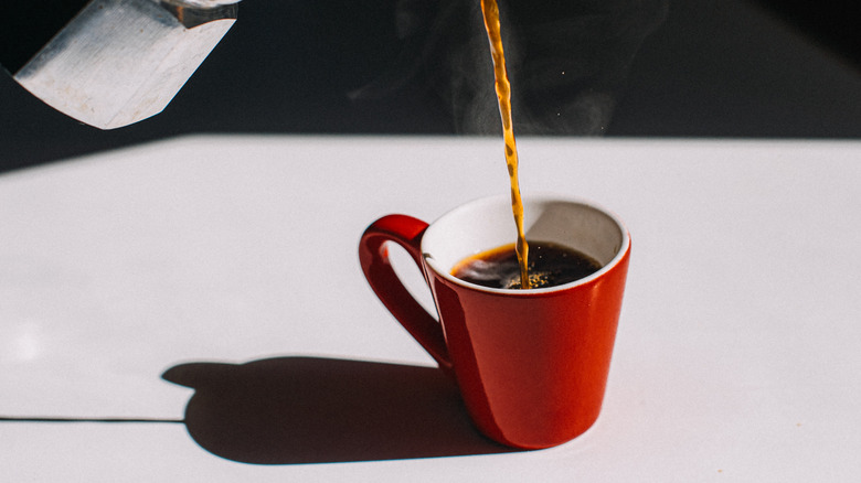 Coffee being poured into a red mug