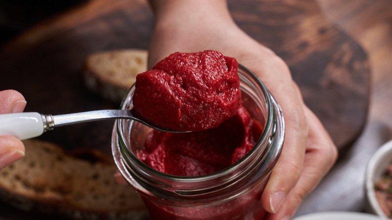 Scooping tomato paste from jar