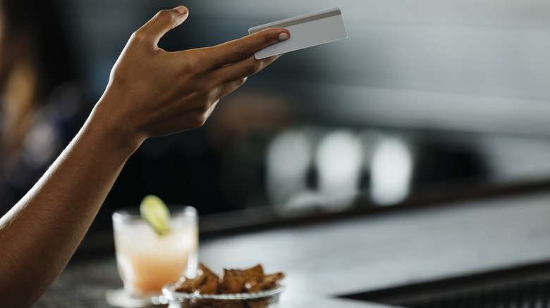 person paying for whiskey cocktail at bar