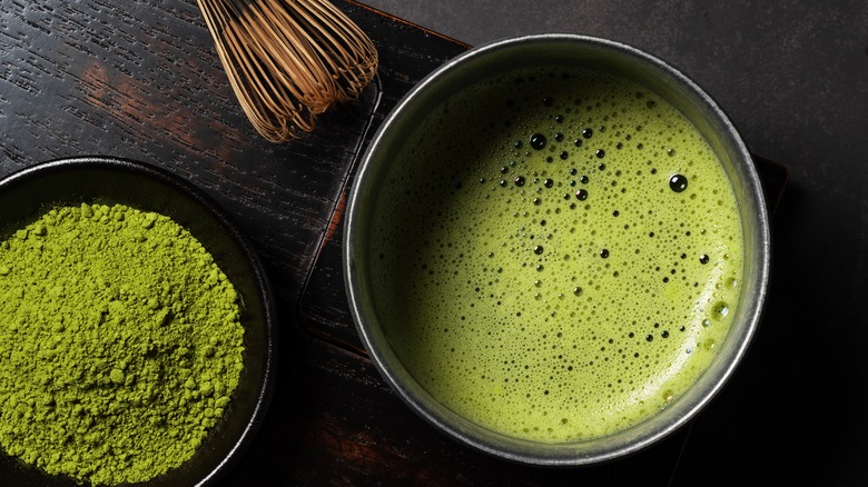 Dry matcha and hot matcha tea against a dark background