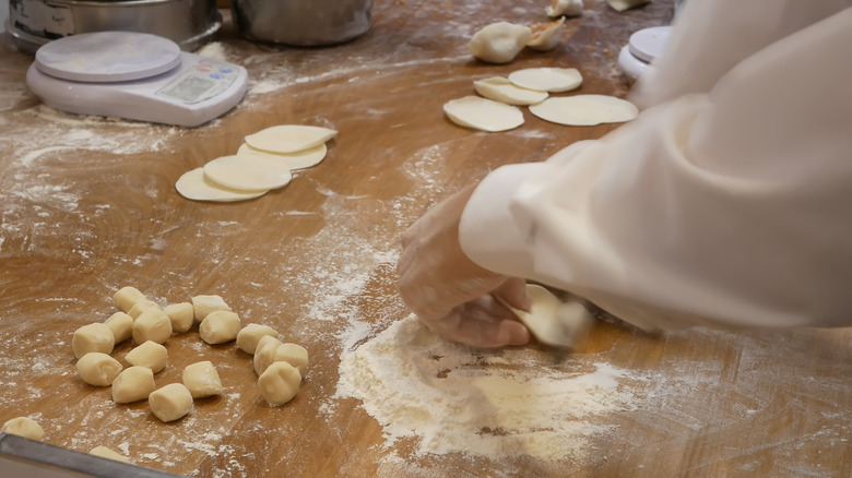 Dumpling wrappers being made on a wooden board