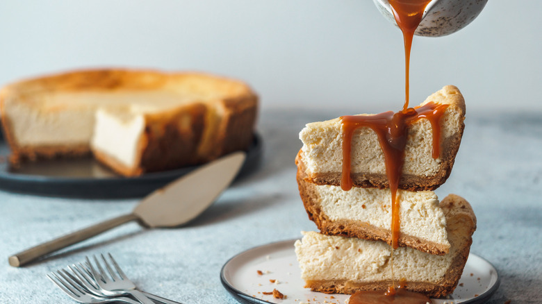 Slices of cheesecake being drizzled with caramel sauce.