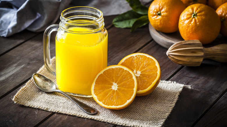 glass of orange juice with orange halves