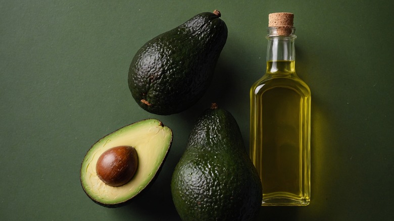 Avocados and avocado oil on green background