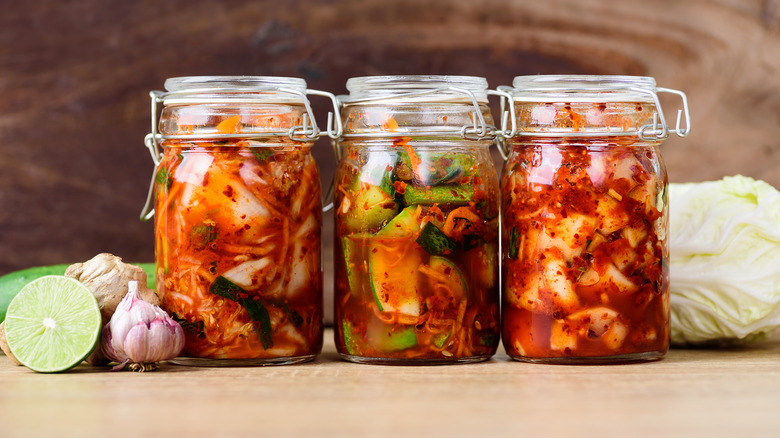 Three jars of kimchi and fermented products on a counter