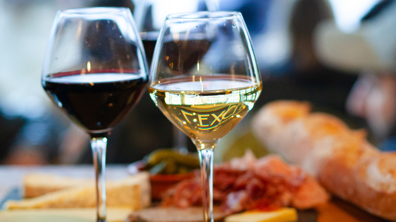 A glass of red wine and a glass of white with typical apero snacks in background