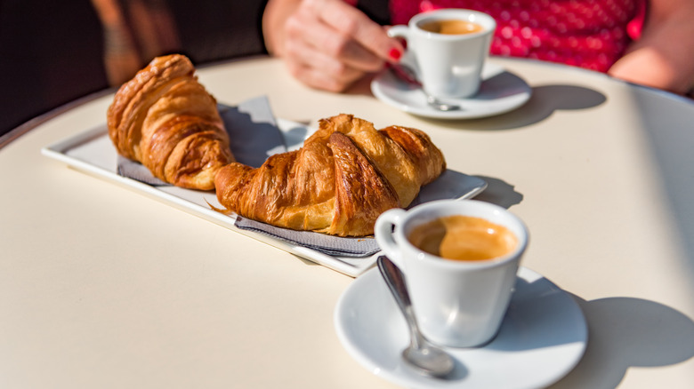 Two croissants and two small cups of Paris-style coffee on a table