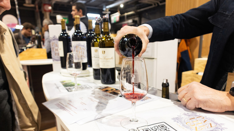 Person pouring wine with a selection of bottles beside him on a table