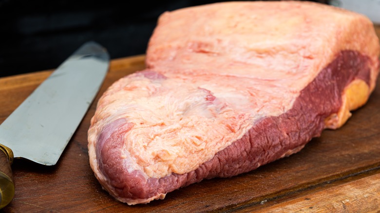 raw brisket displayed with knife