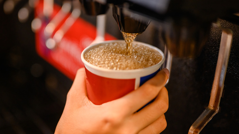 Filling cup with soda at fast food drink fountain