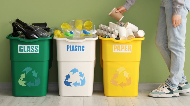 Recycling bins full of glass, paper, and plastic items