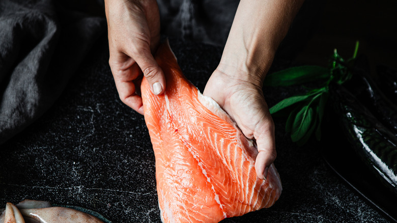 Hands inspecting a salmon fillet