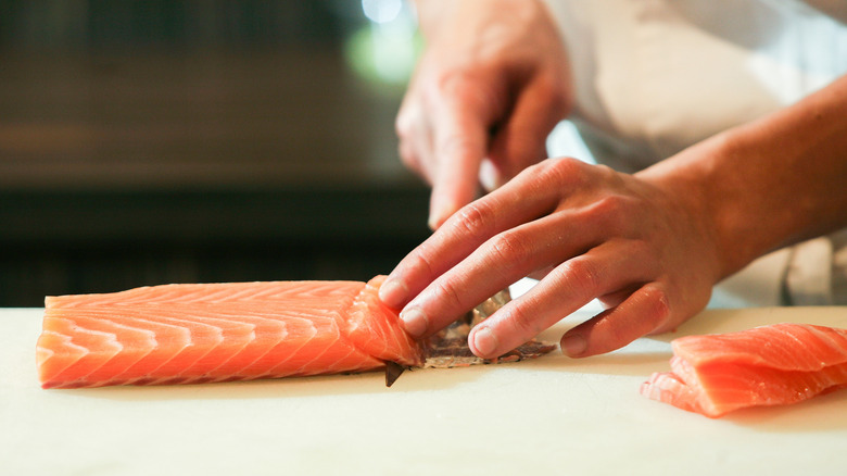 Person slicing salmon into sashimi