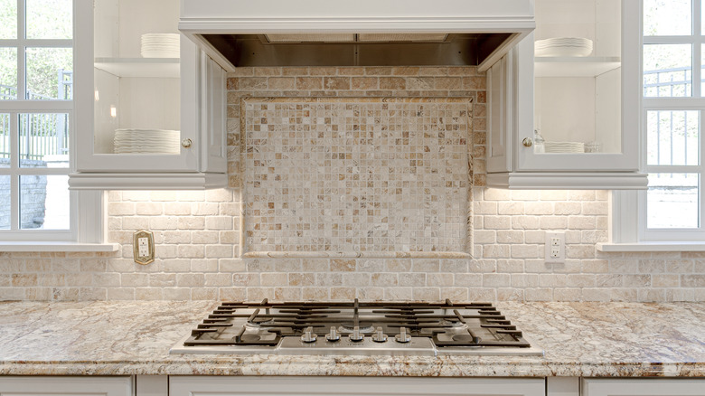 Limestone backsplash and countertops in an open white kitchen