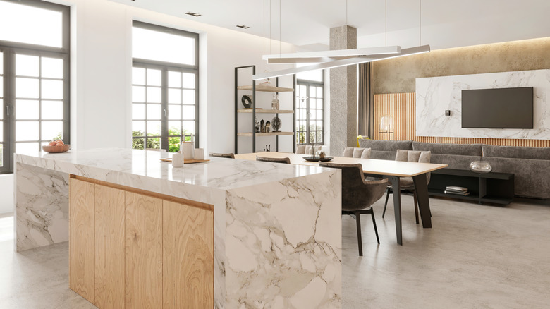 A dolomite kitchen island stands in the foreground with a dining table and living room in the background