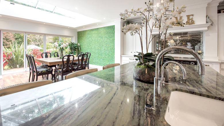 Low angle view of a quartzite countertop with dining room table and green wall in the background