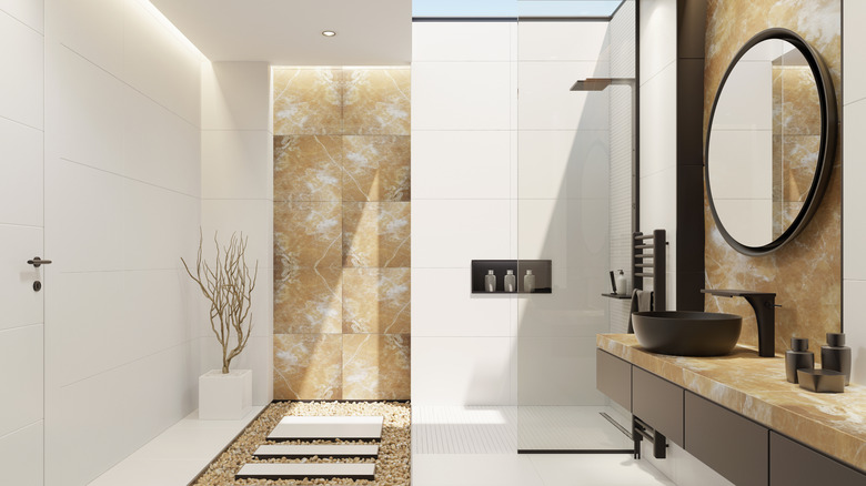 A gold onyx wall and countertop in a large white bathroom