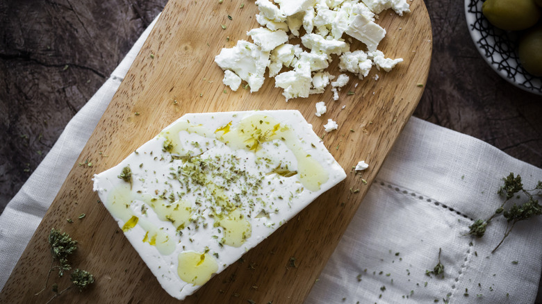 Crumbled feta on a wooden cutting board.